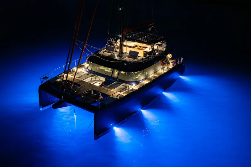  Yacht Photos Pics 2024 Sunreef 60 Eco yacht illuminated at night with vibrant blue underwater lights.