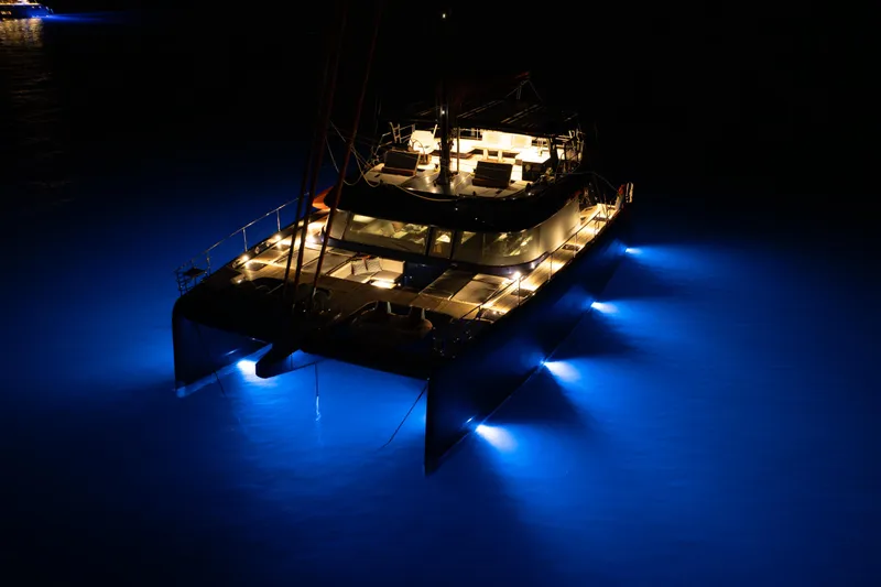 Yacht Photos Pics 2024 Sunreef 60 Eco yacht illuminated at night with vibrant blue underwater lights.