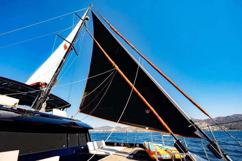  Yacht Photos Pics 2024 Sunreef 60 Eco yacht sailing with black sails under clear blue sky.