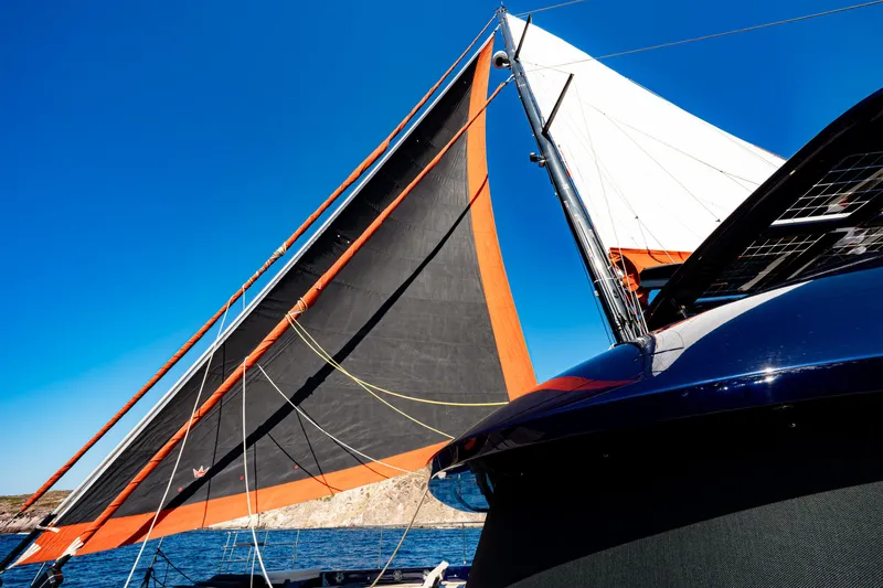  Yacht Photos Pics 2024 Sunreef 60 Eco yacht with vibrant sails against a clear blue sky.