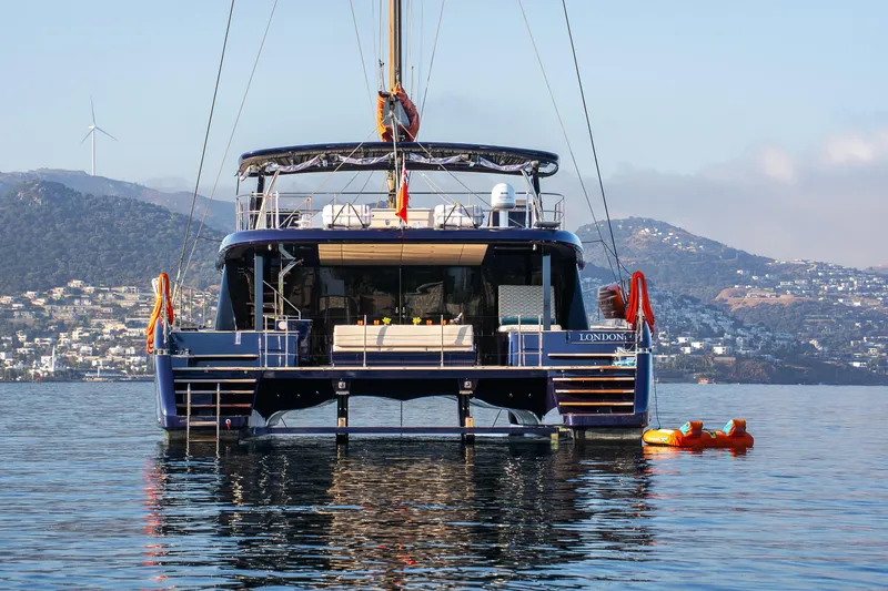  Yacht Photos Pics 2024 Sunreef 60 Eco yacht on calm water with scenic mountain backdrop.