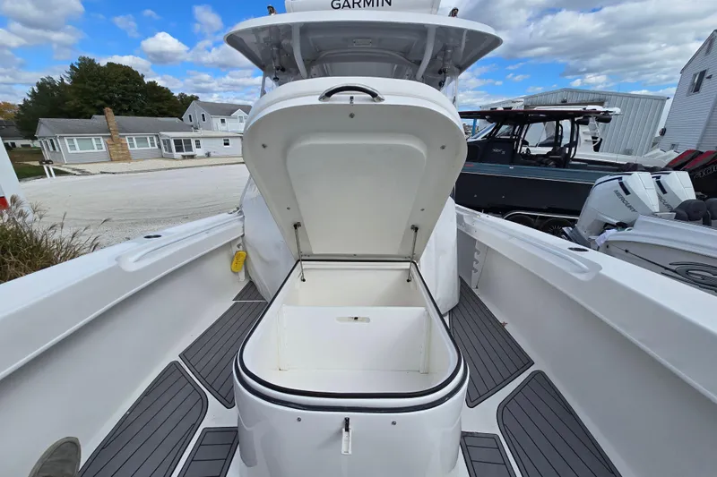  Yacht Photos Pics 2021 Twin Vee 310 CC GF boat with open storage compartment, docked under a cloudy sky.