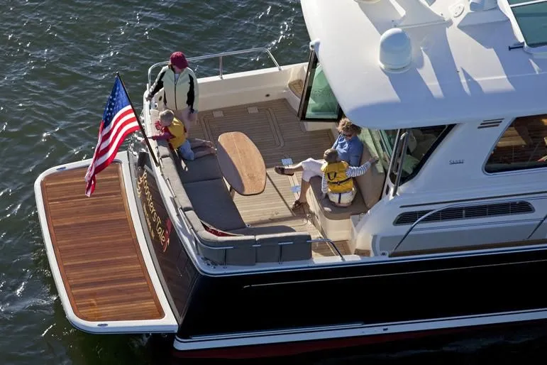 Vertical Yacht Photos Pics 2017 Sabre 48 Salon Express yacht with people on deck, American flag, and wooden swim platform.