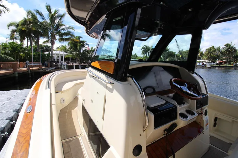 Lilaia Yacht Photos Pics 2020 Chris-Craft Catalina 34 boat interior with steering wheel, docked by palm trees.
