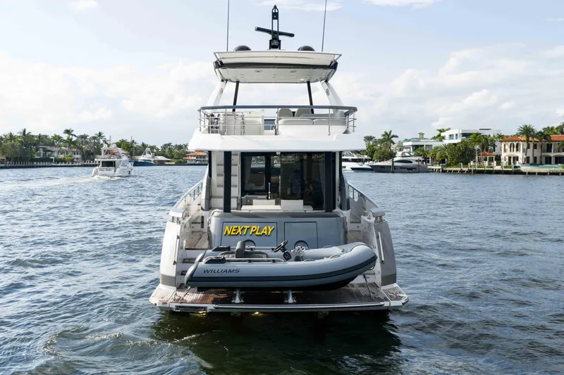 Next Play Yacht Photos Pics 2024 Azimut Fly 68 yacht with tender, cruising in a scenic waterfront setting.