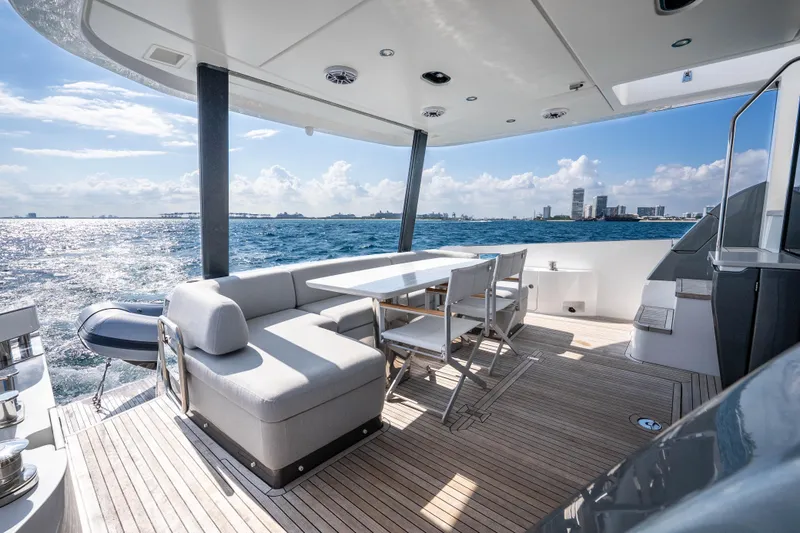 Next Play Yacht Photos Pics Luxurious 2024 Azimut Fly 68 yacht deck with seating, ocean view, and city skyline.