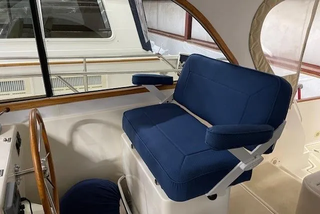 Picnic Boat Yacht Photos Pics Captain's chair on 2003 Legacy Yachts 34 Express, featuring blue upholstery and wooden accents.