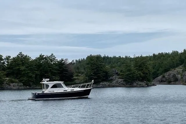 Picnic Boat Yacht Photos Pics 2003 Legacy Yachts 34 Express cruising on a serene lake with lush green trees.