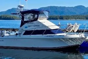 1997 Skipjack 262 Flybridge boat on water with scenic mountain backdrop.