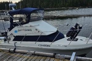 1997 Skipjack 262 Flybridge boat docked by a serene lake with forest backdrop.