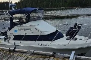 1997 Skipjack 262 Flybridge boat docked by a serene lake with forest backdrop.