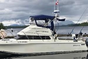 1997 Skipjack 262 Flybridge boat docked on a cloudy day with scenic background.