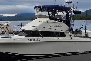 1997 Skipjack 262 Flybridge boat docked by a scenic lake.