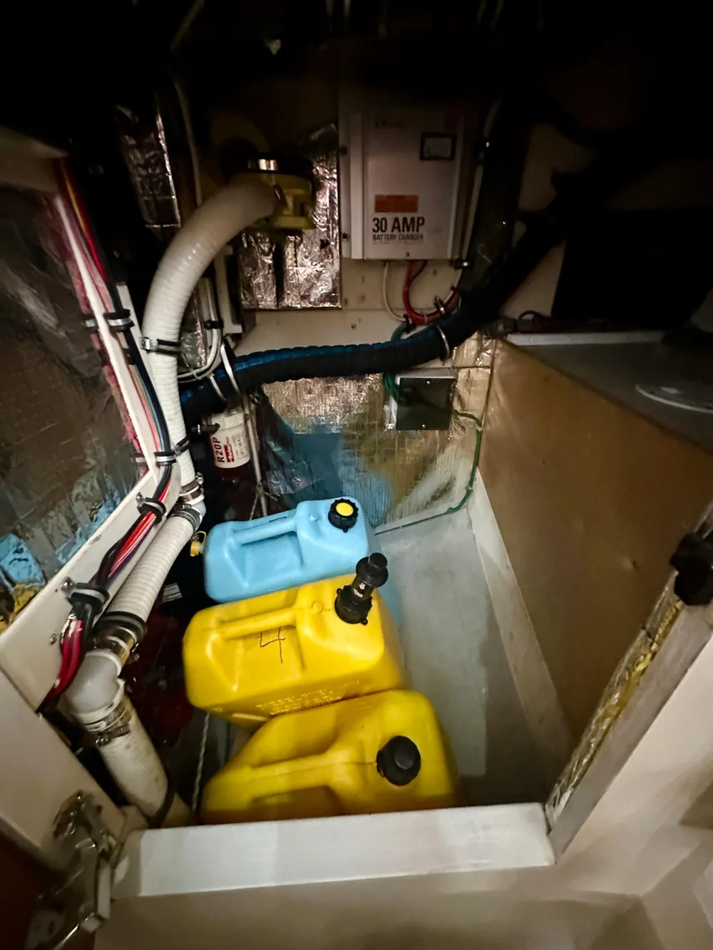 Engine compartment of a 1996 Valiant 39 with fuel containers and electrical components.