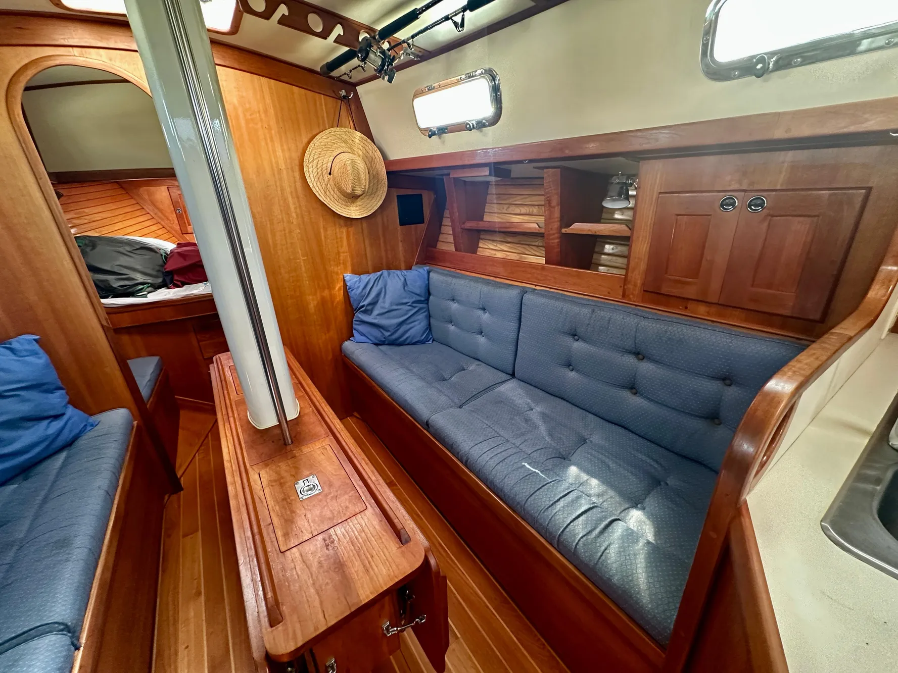 Cozy interior of 1996 Valiant 39 sailboat with wooden furnishings and blue cushions.