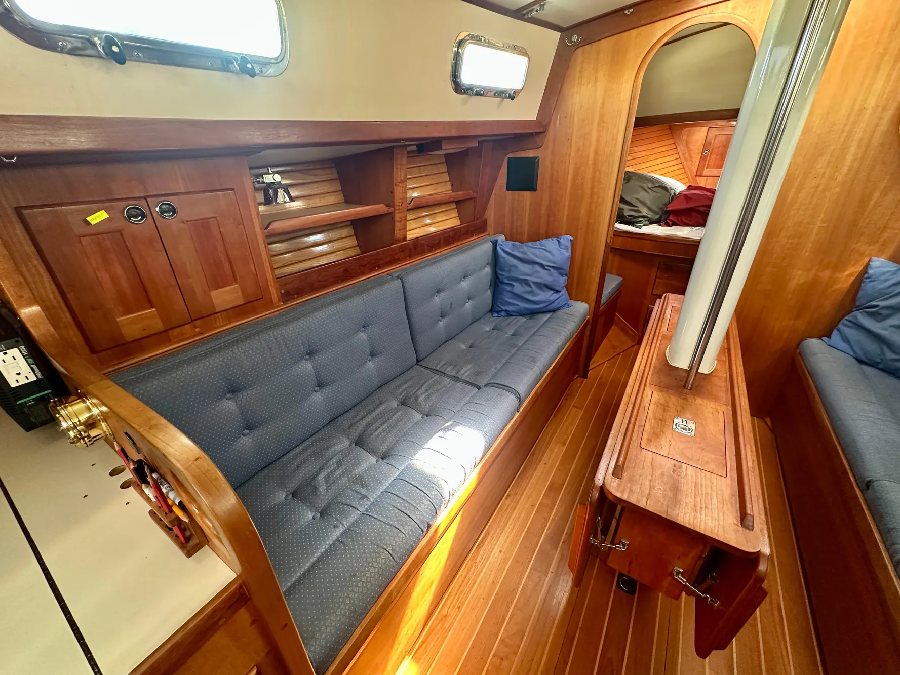 Interior of a 1996 Valiant 39 sailboat with wooden furnishings and blue cushions.