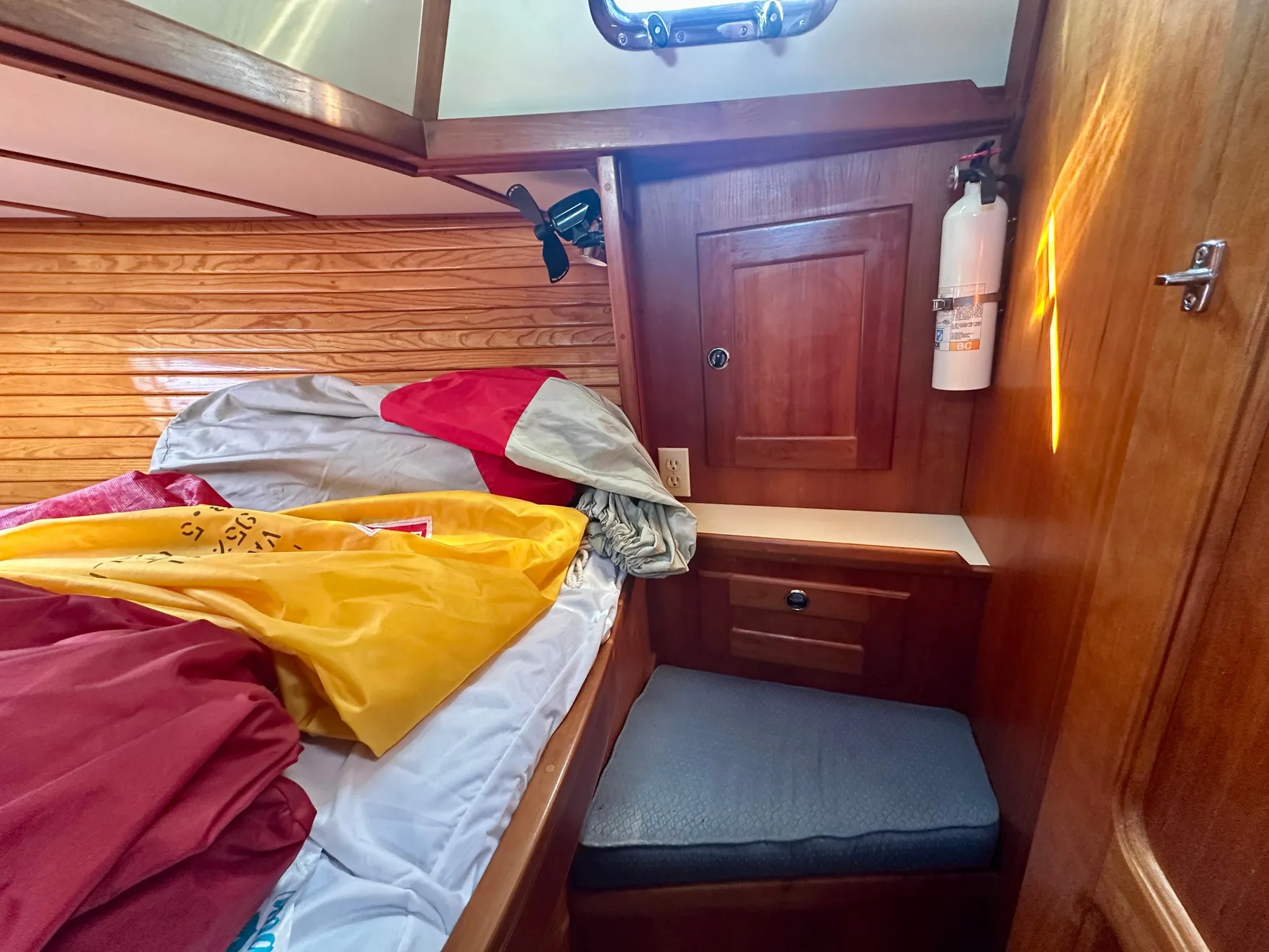 Cozy cabin interior of a 1996 Valiant 39 sailboat with wooden paneling and colorful bedding.