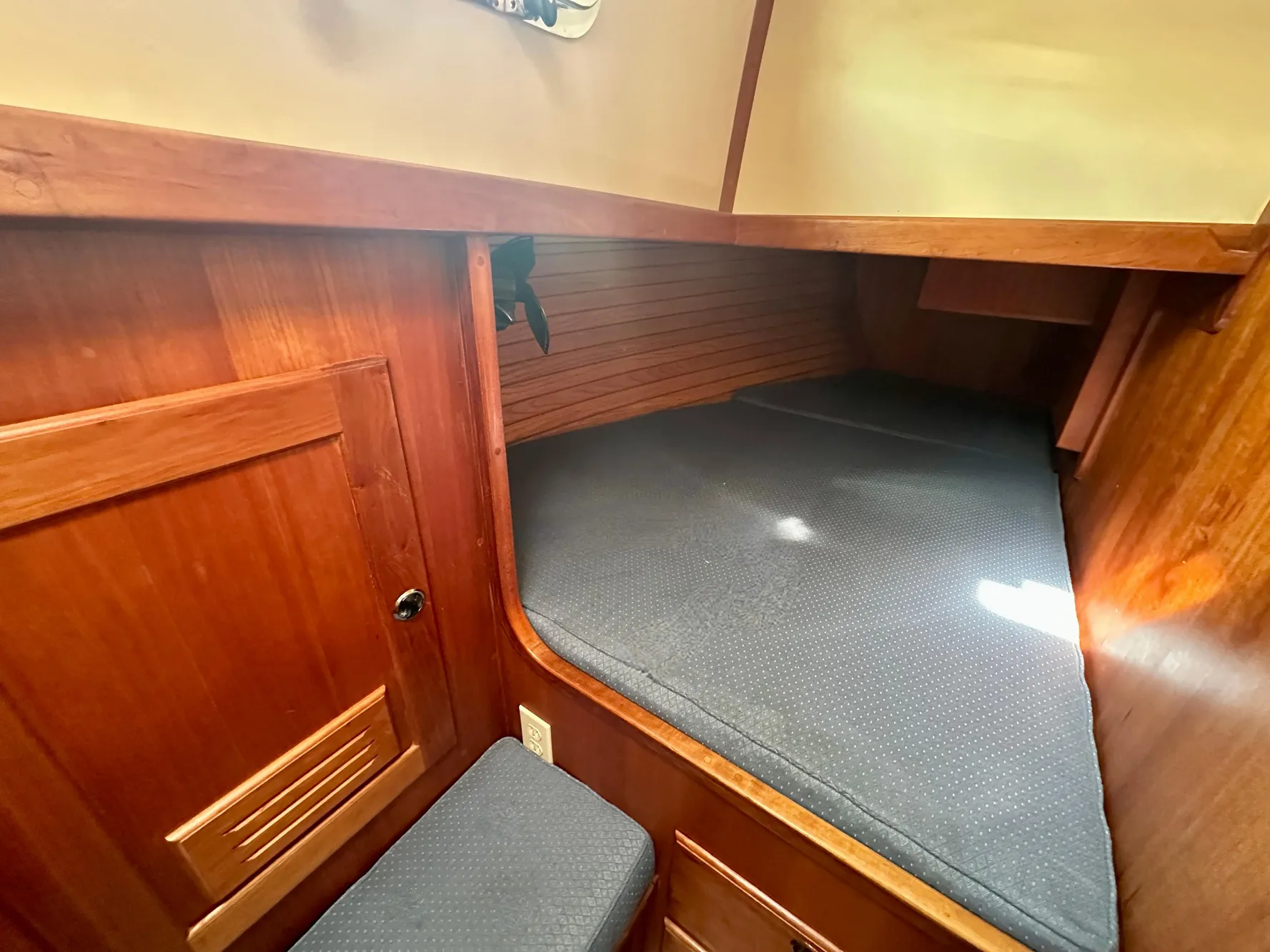 Cozy wooden cabin interior of 1996 Valiant 39 sailboat with cushioned sleeping area.