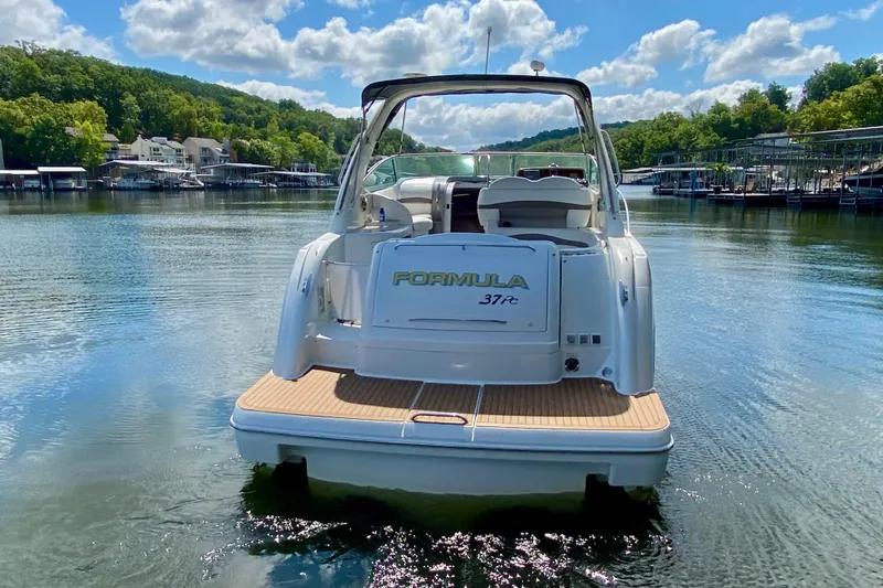  Yacht Photos Pics 2004 Formula 37 PC boat on a serene lake with lush green surroundings.