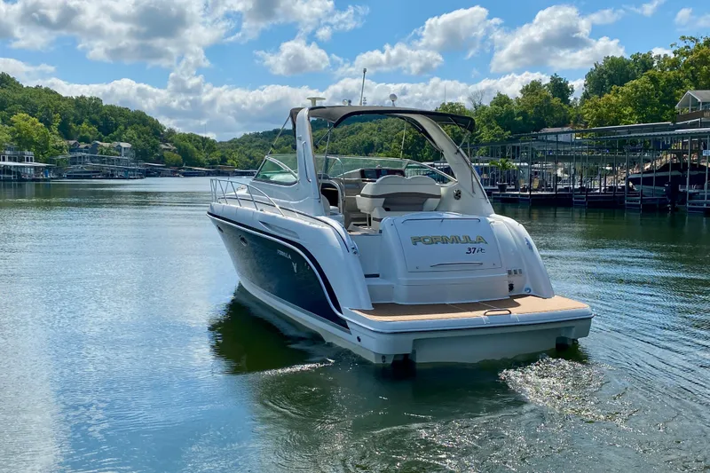  Yacht Photos Pics 2004 Formula 37 PC boat cruising on a serene lake under a partly cloudy sky.