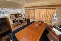 Interior of 1998 ACM Heritage 26 boat with wooden table and cozy seating.