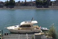 1998 ACM Heritage 26 boat docked on a serene river with cityscape background.