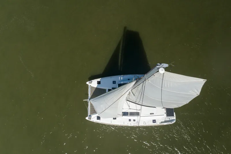  Yacht Photos Pics Aerial view of 2021 Lagoon 450 s catamaran sailing on calm green water.