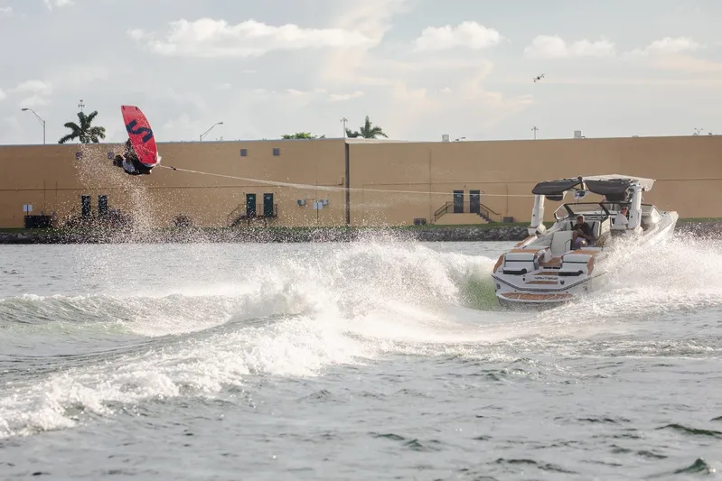  Yacht Photos Pics Wakeboarder jumps behind 2025 Nautique Super Air Nautique G25 Paragon on a sunny day.