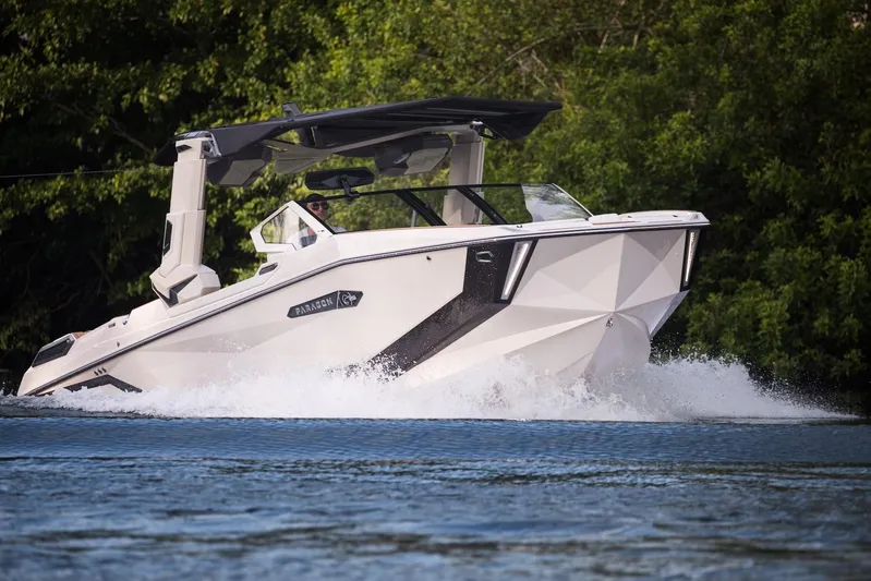  Yacht Photos Pics 2025 Nautique Super Air Nautique G25 Paragon cruising on water, surrounded by lush greenery.