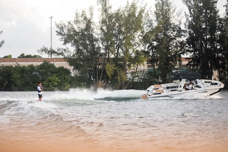  Yacht Photos Pics Wakeboarder riding behind 2025 Nautique Super Air Nautique G25 Paragon on a scenic lake.