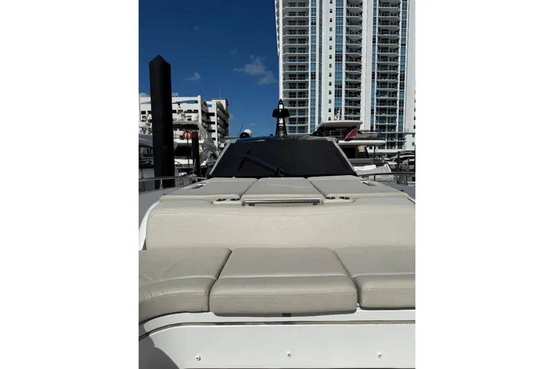 Chicken Money Yacht Photos Pics 2023 Azimut Verve 47 yacht with beige seating, docked near modern high-rise buildings.