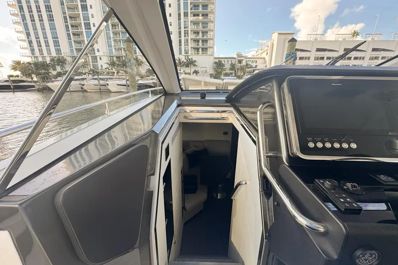 Chicken Money Yacht Photos Pics 2023 Azimut Verve 47 yacht interior with control panel, docked near modern buildings.