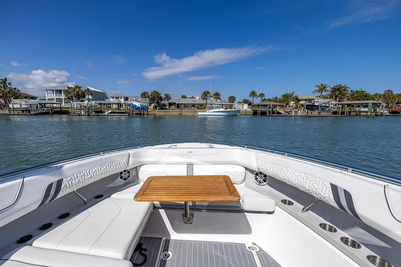 Absolutely Knot Yacht Photos Pics 2022 Regal LX36 boat interior with seating and table, docked by waterfront homes.