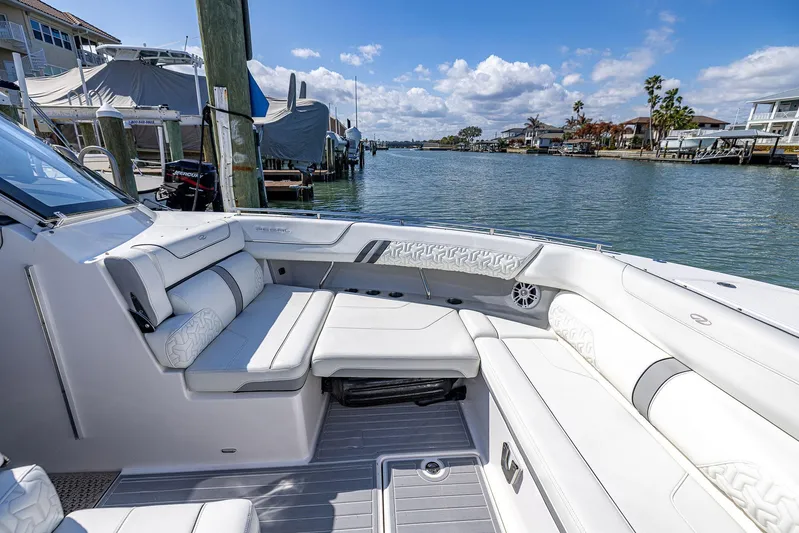 Absolutely Knot Yacht Photos Pics Luxurious 2022 Regal LX36 boat interior with plush seating, docked by a scenic waterfront.