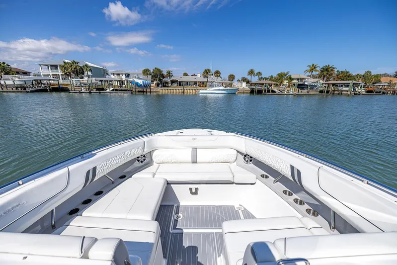 Absolutely Knot Yacht Photos Pics 2022 Regal LX36 boat with luxurious seating, docked near waterfront homes under a clear blue sky.