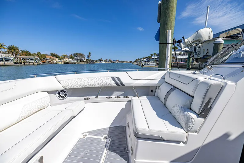 Absolutely Knot Yacht Photos Pics Luxurious 2022 Regal LX36 boat interior with white seating, docked by a scenic waterfront.