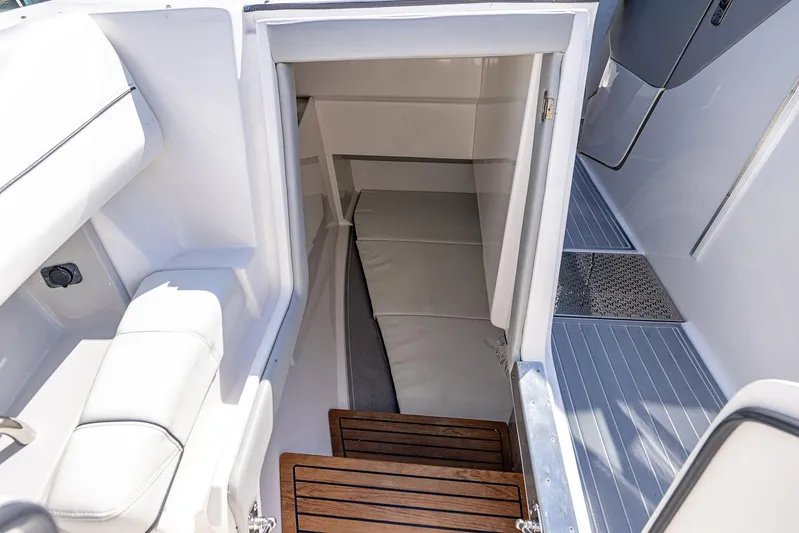 Absolutely Knot Yacht Photos Pics Interior cabin view of 2022 Regal LX36 boat, featuring sleek white seating and wooden steps.