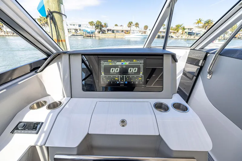 Absolutely Knot Yacht Photos Pics 2022 Regal LX36 boat dashboard with digital display and cup holders, docked by the water.
