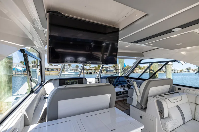 Absolutely Knot Yacht Photos Pics Interior of 2022 Regal LX36 yacht with modern helm, seating, and large TV screen.