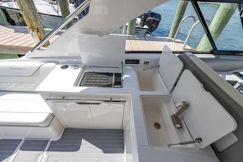 Absolutely Knot Yacht Photos Pics 2022 Regal LX36 boat interior with kitchenette and sink, docked by the water.
