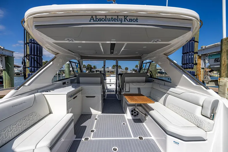 Absolutely Knot Yacht Photos Pics 2022 Regal LX36 luxury boat interior with white seating and wooden table, docked at marina.