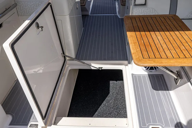 Absolutely Knot Yacht Photos Pics 2022 Regal LX36 boat interior with open storage hatch and wooden table.