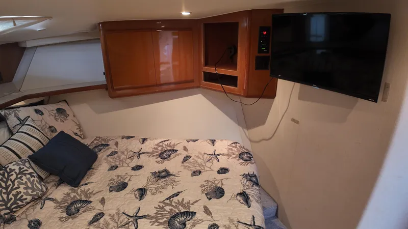  Yacht Photos Pics Cozy bedroom in 1999 Viking 47 Convertible yacht with TV and nautical-themed bedding.