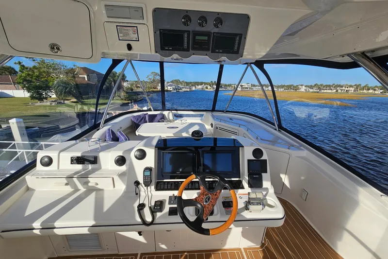 Low Hours! Yacht Photos Pics 2006 Sea Ray 580 Sedan Bridge helm with modern controls and scenic waterway view.