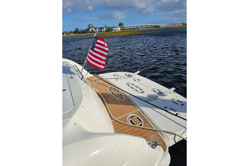 Low Hours! Yacht Photos Pics 2006 Sea Ray 580 Sedan Bridge yacht with American flag on deck, near shoreline.