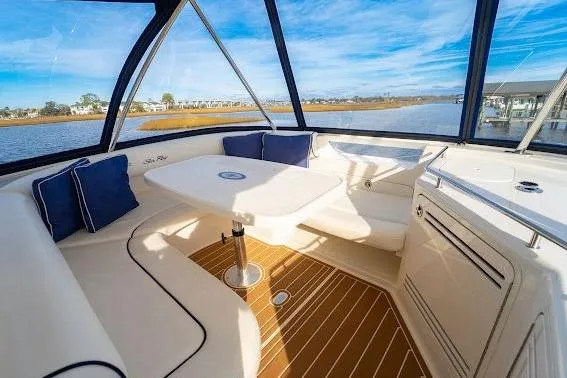 Low Hours! Yacht Photos Pics 2006 Sea Ray 580 Sedan Bridge interior with seating and table, overlooking serene water views.