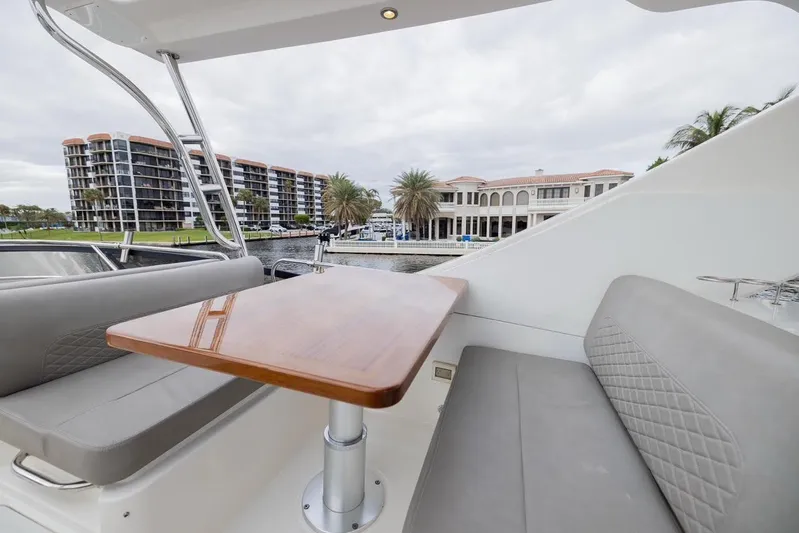 Andiamo Yacht Photos Pics 2017 Sea Ray 59 Flybridge yacht with elegant seating and table, overlooking waterfront buildings.