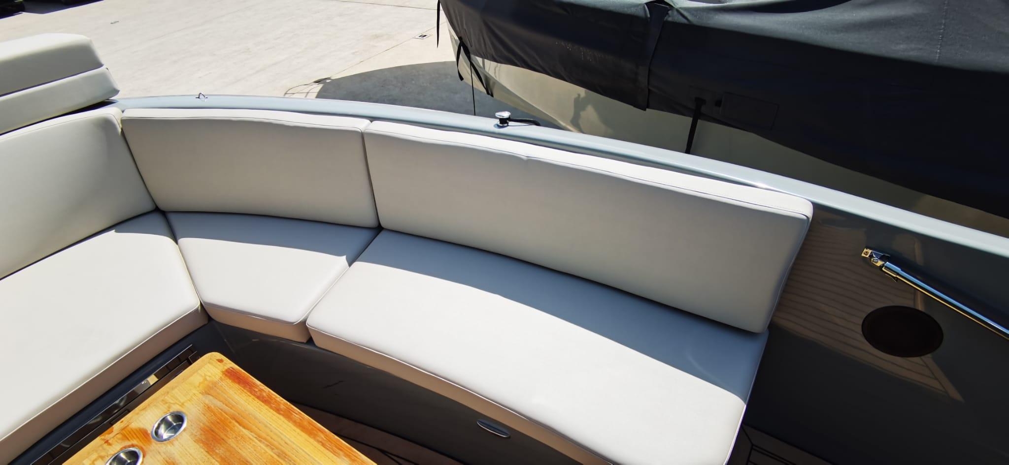 Luxurious seating area on a 2022 Rand PLAY 24 boat with wooden table.