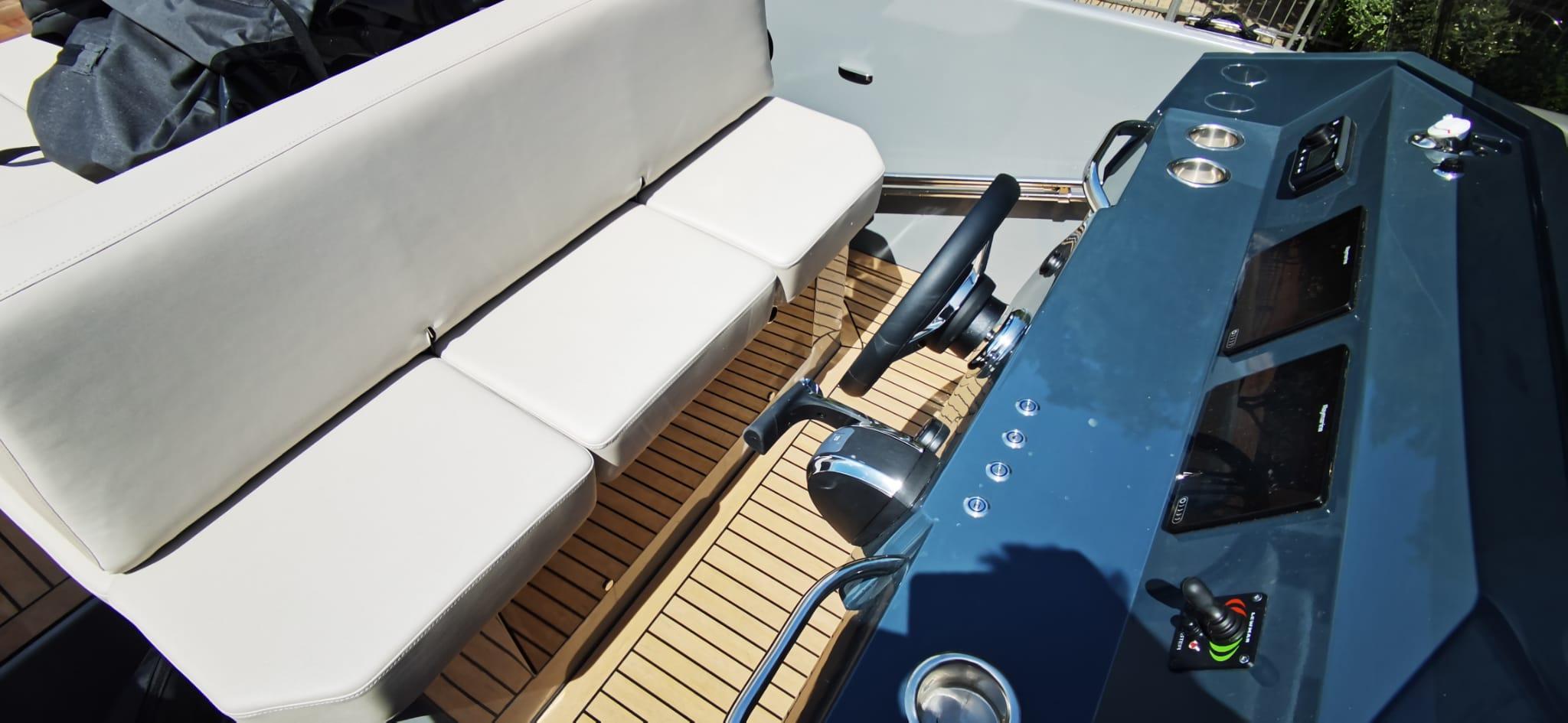 Interior of 2022 Rand PLAY 24 boat with steering wheel and cushioned seating.