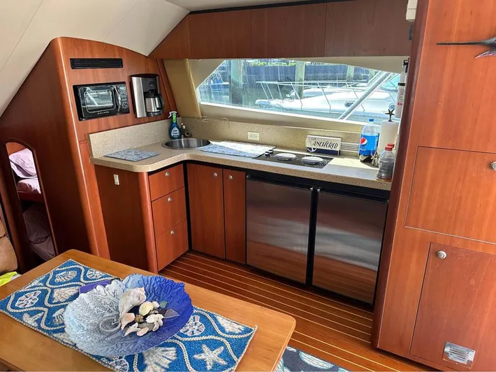  Yacht Photos Pics 2005 Luhrs 36 Convertible yacht interior with kitchenette, featuring wood cabinetry and modern appliances.